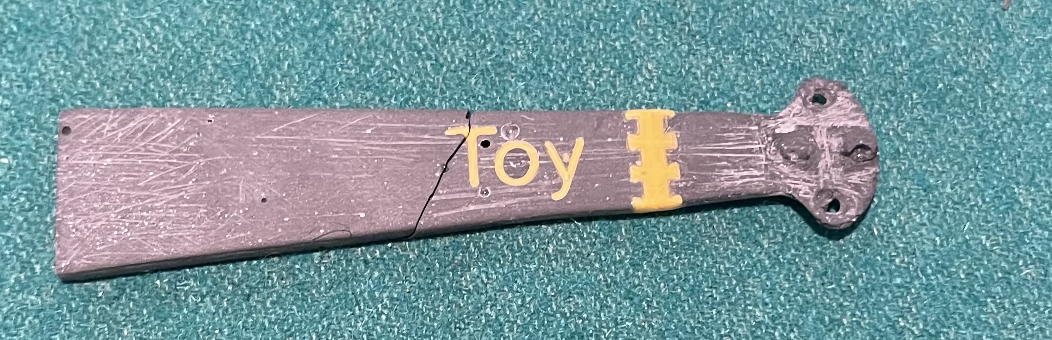 Physical photograph of the tip showing the PLA segmentation link with TOY lettering and the dovetail interlocked sections